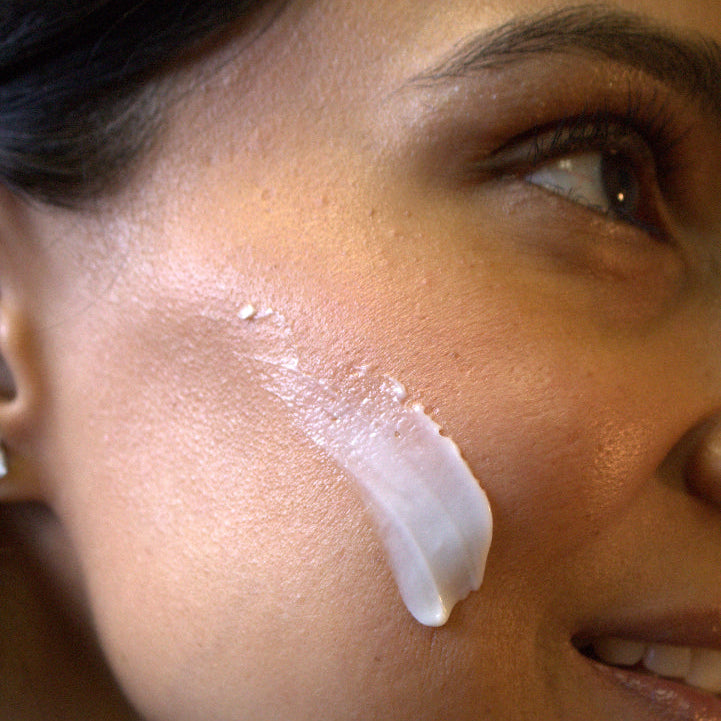 Close-up of a woman's face with a smear of cream on her cheek.